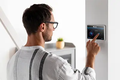 man using wall-mounted home security system control panel