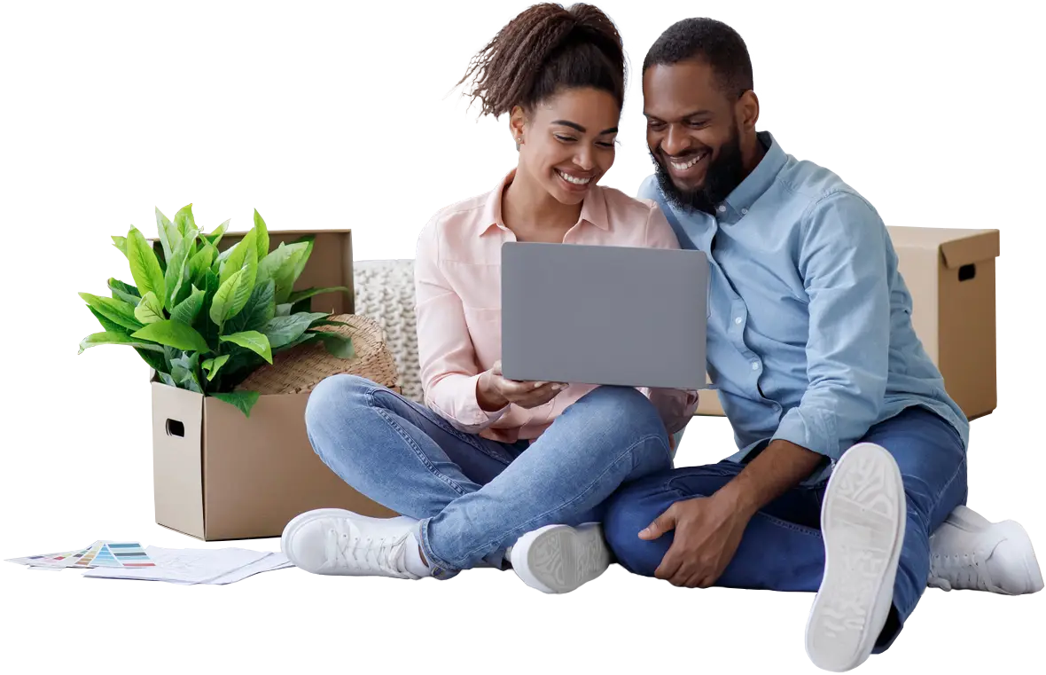 photo of young couple sitting on the floor looking at a laptop together, surrounded by moving boxes